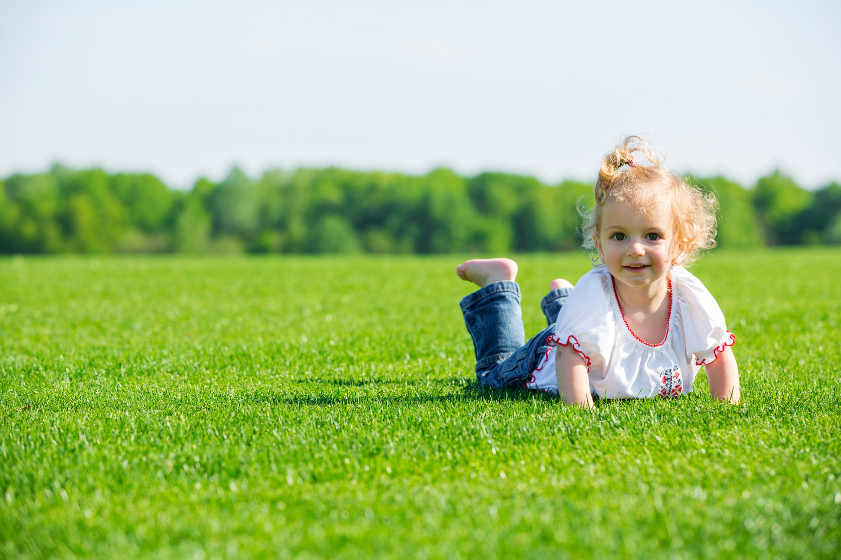 Szczęśliwa mała dziewczynka bawi się na trawie