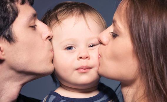 Rodzice całują dziecko z policzki