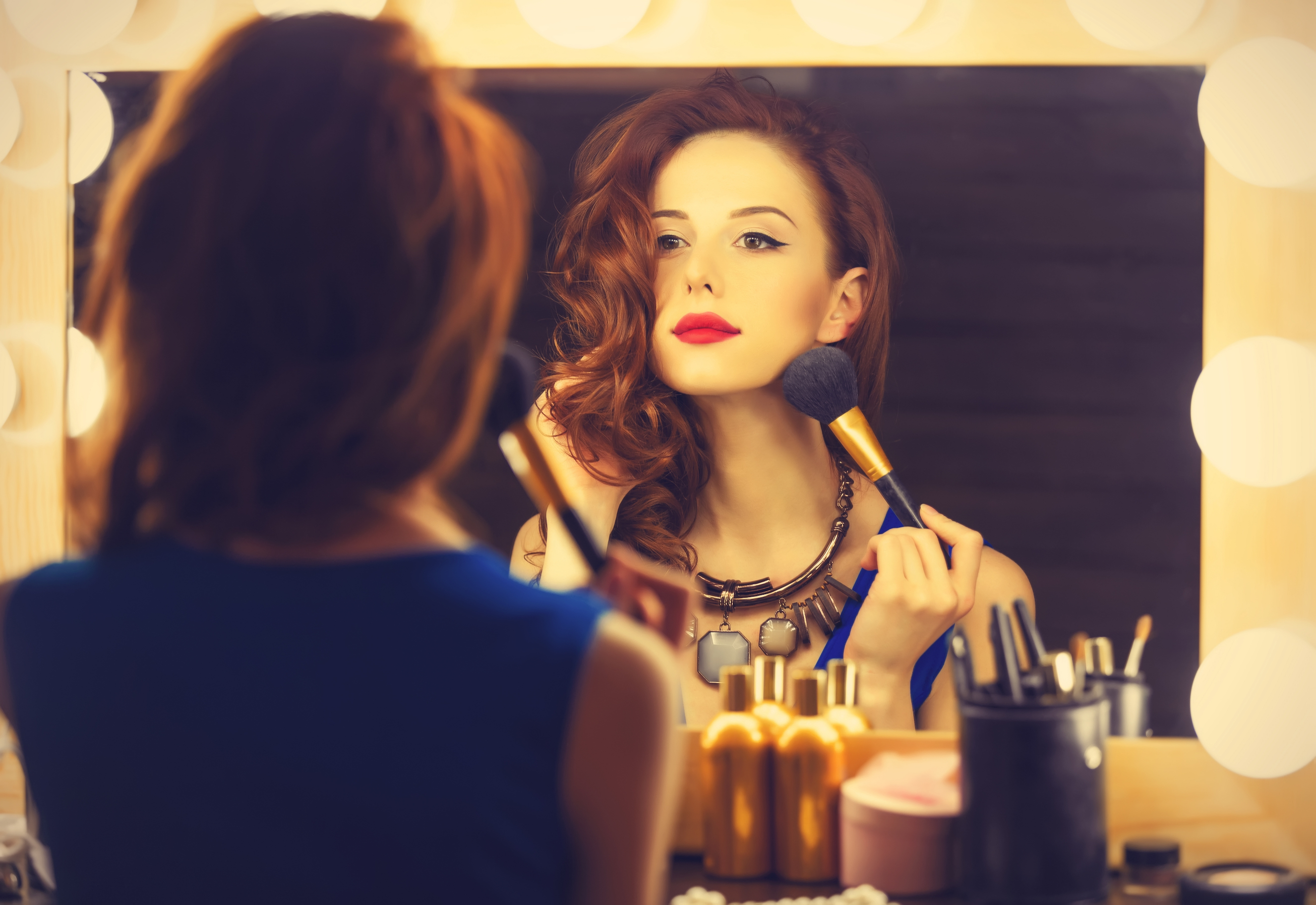 Kobieta przed lustrem robi sobie makijaż
