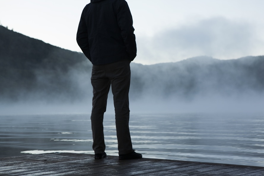 Mężczyzna stoi nad brzegiem jeziora